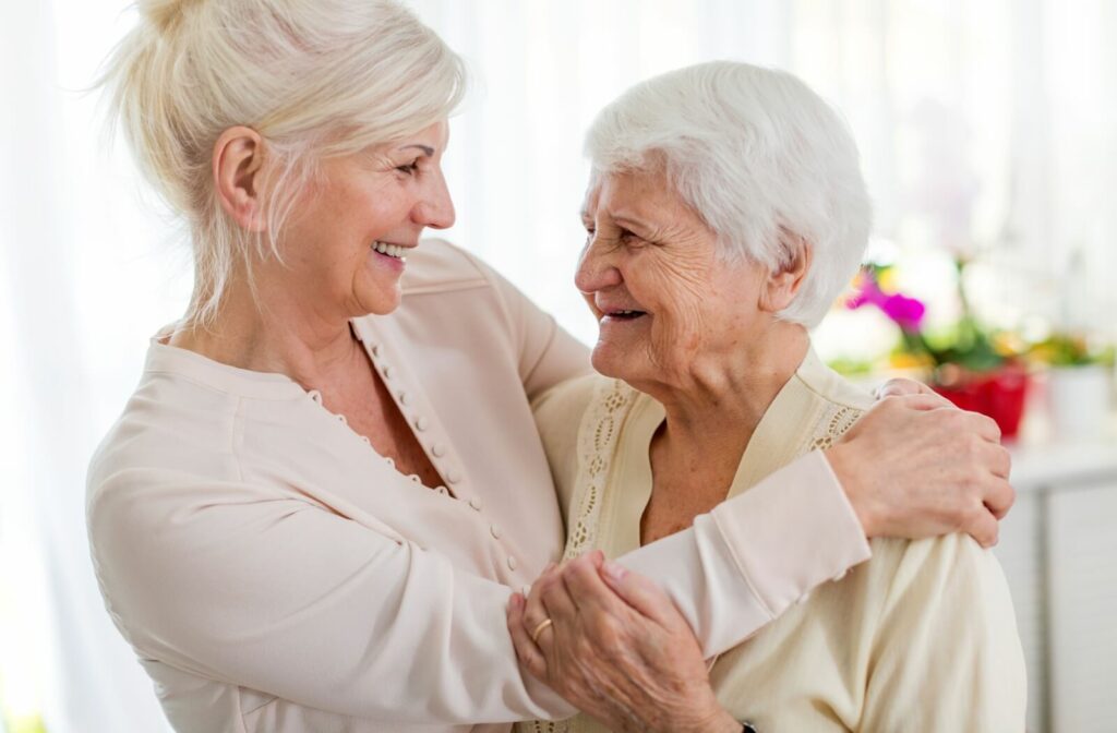 A woman smiling and hugging her senior mother