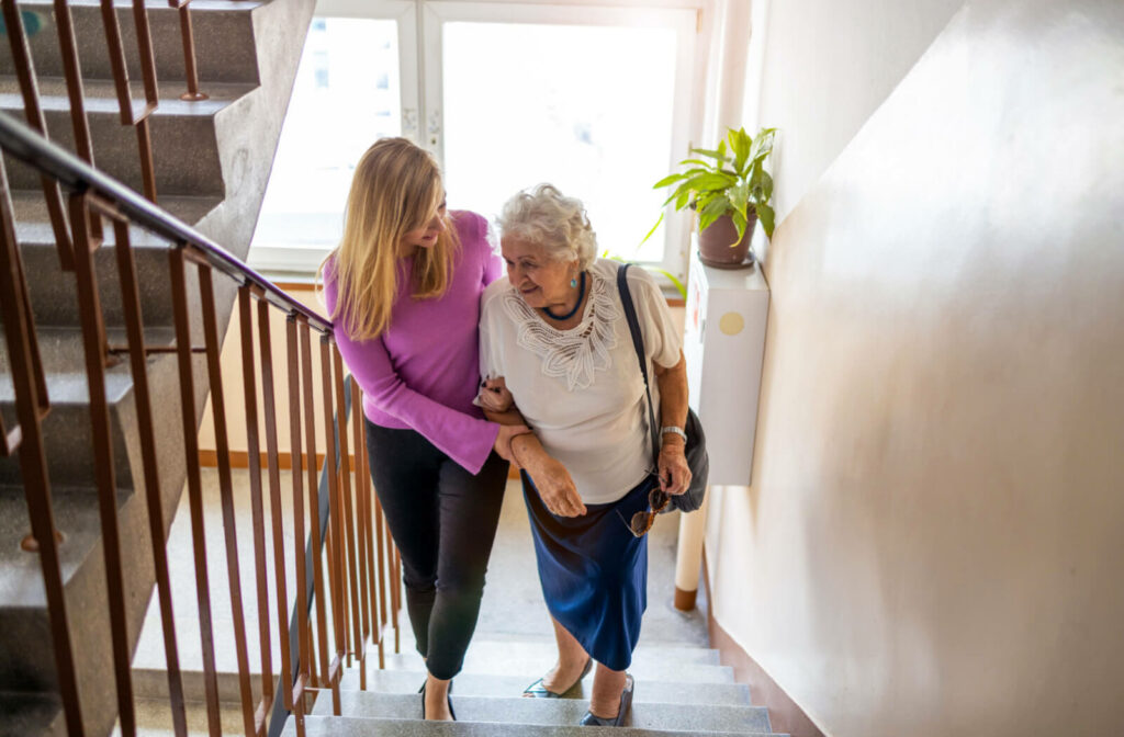 a woman helping a senior up the stairs while visiting memory care communities