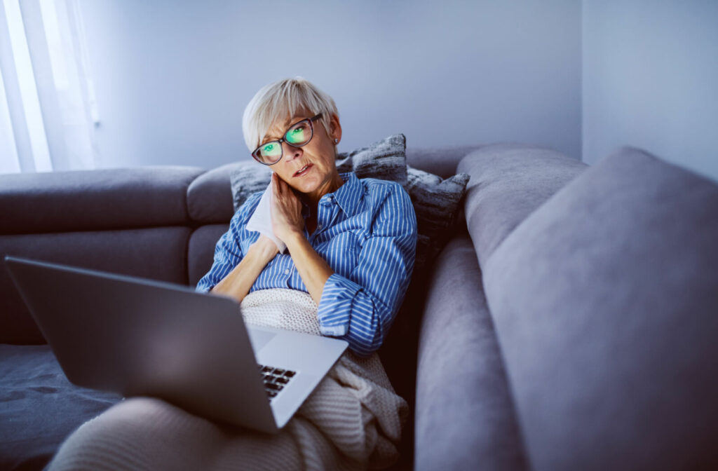 An older adult watching a late-night movie about Alzheimer's disease, clutching a tissue and feeling overwhelmed with emotion.